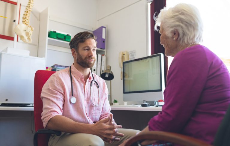 Male Doctor And Senior Woman Interacting With Each Other In Clinic